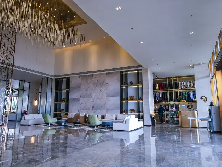 Hotel lobby with a polished marble floor, lounge seating and a large chandelier
